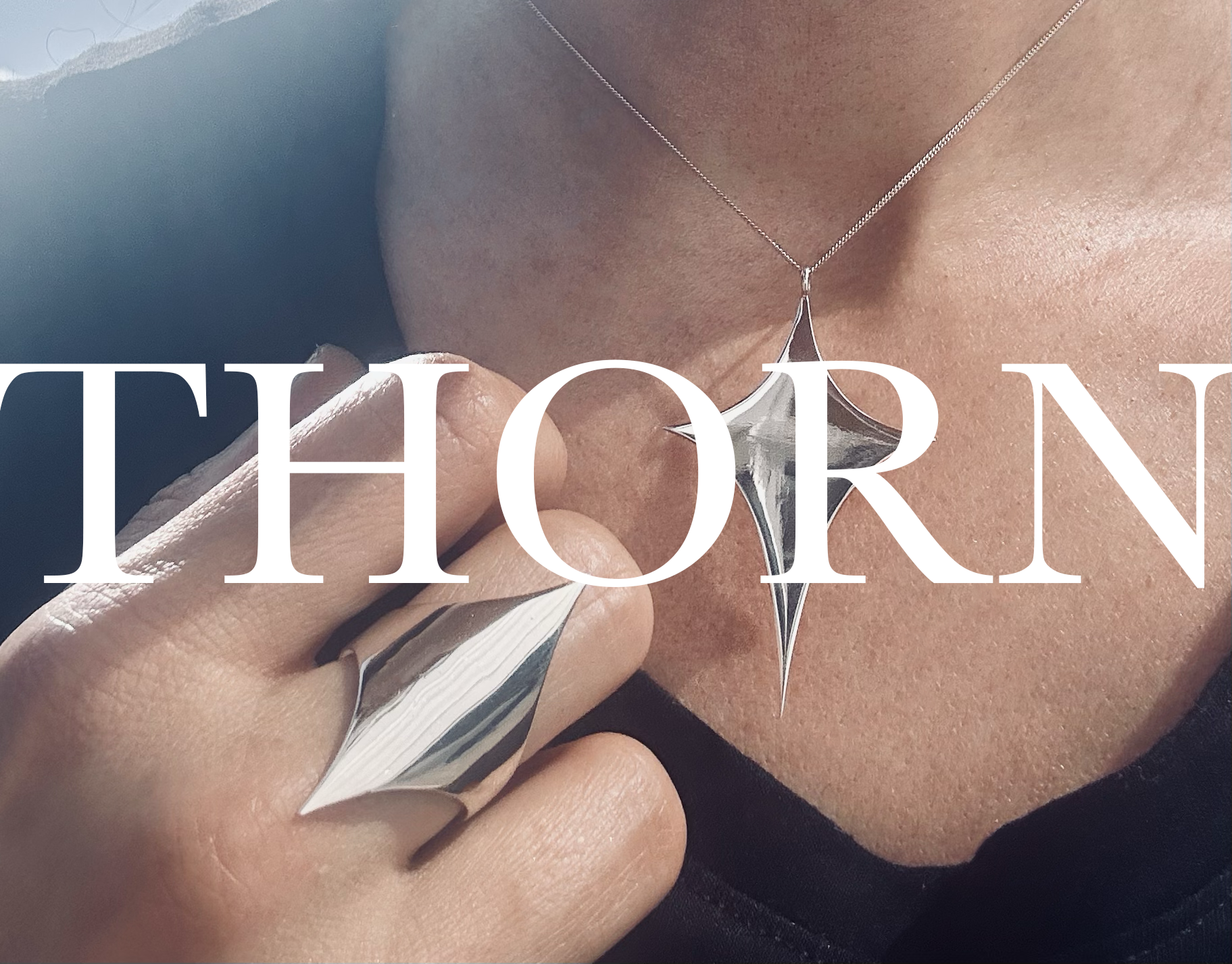 A close-up lifestyle shot of a person wearing a silver pendant necklace and a matching silver ring, with the word 'THORN' overlaid in large white text across the center.